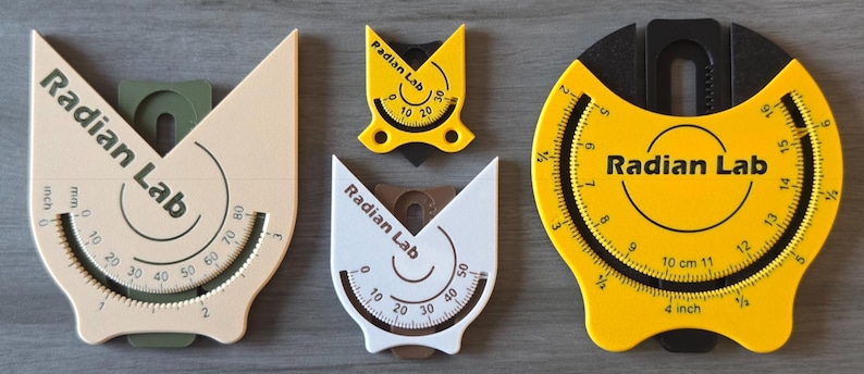 May include: A collection of Radian Lab angle finders in various sizes and colors. The tools are beige, white, and yellow, with black and green accents. Each tool features a curved scale with measurements in inches and centimeters. The text "Radian Lab" is printed on each tool.