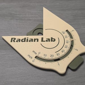 May include: A beige and gray protractor with the text "Radian Lab". The protractor has inch and millimeter measurements, and a degree scale from 0 to 80. The tool is designed for measuring angles.