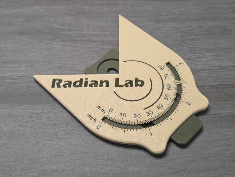 May include: A beige and gray protractor with the text "Radian Lab". The protractor has inch and millimeter measurements, and a degree scale from 0 to 80. The tool is designed for measuring angles.