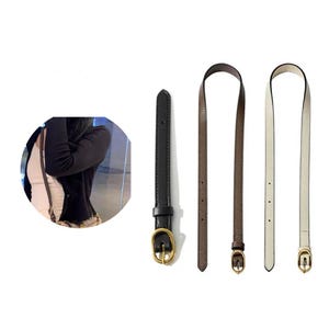 May include: Three leather purse straps in black, brown, and off-white. Each strap has a gold-colored buckle. The black strap is shorter than the other two. The straps are displayed against a white background.