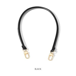 May include: A black handbag handle with gold-colored clasps. The handle is curved and made of a smooth, possibly leather-like material. The word "BLACK" is printed at the bottom of the image.