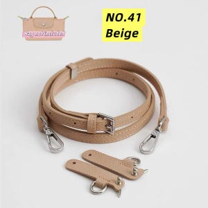 Pode incluir: Uma alça de bolsa ajustável bege com ferragens metálicas prateadas, incluindo dois mosquetões, e duas abas de aspecto couro bege combinando com anéis e tachas metálicas. O texto NO.41 Beige é visível no canto superior direito.