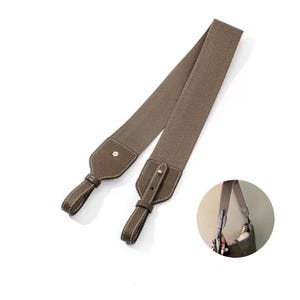 May include: A brown bag strap with a woven fabric center and leather ends. The leather ends are detailed with white stitching and gold-colored rivets. A small, circular image shows the strap attached to a bag.