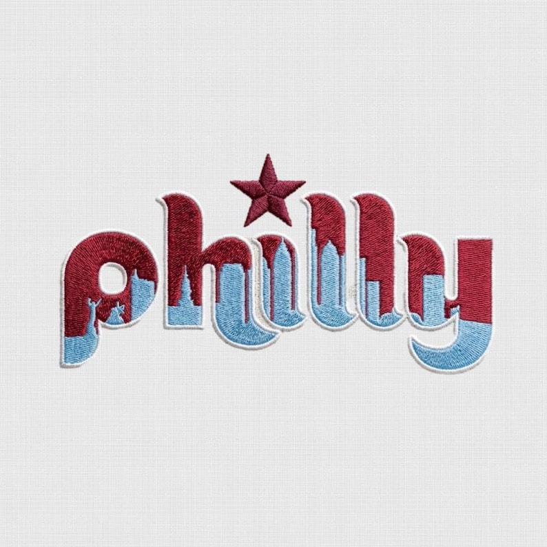 May include: Embroidered patch featuring the word "Philly" in a stylized design. The letters are primarily burgundy with a light blue skyline and accents. A burgundy star sits above the "h". The patch is on a white background.