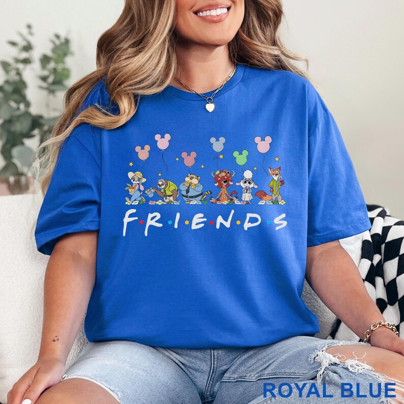 May include: Royal blue t-shirt with the word "FRIENDS" in white, and cartoon characters with Mickey Mouse balloon graphics. The shirt is a vibrant blue and has a relaxed fit.