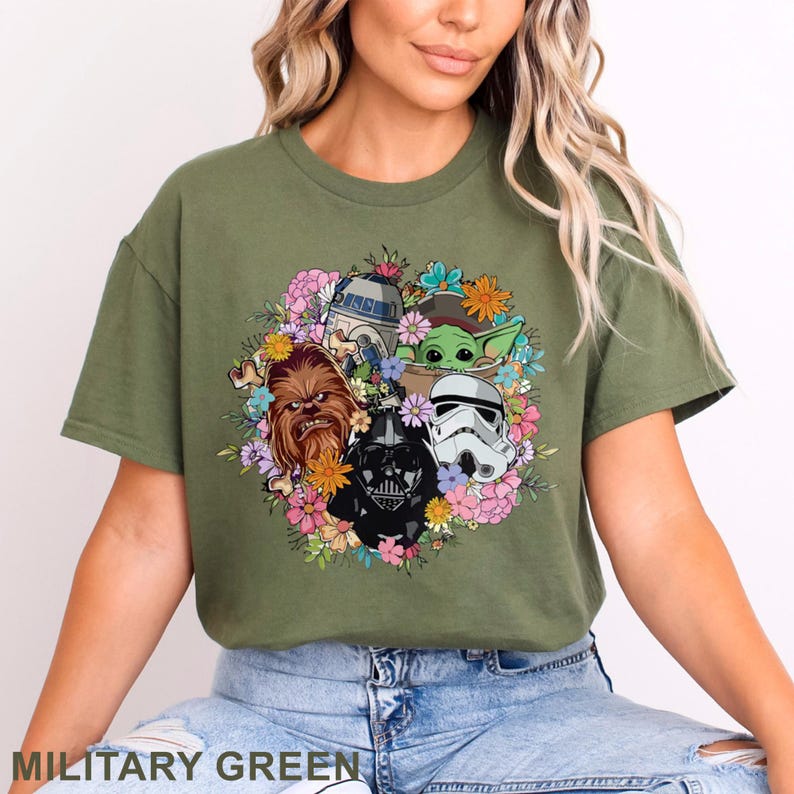 May include: Military green t-shirt featuring a floral design with Star Wars characters including Darth Vader, Chewbacca, and Baby Yoda. The shirt has a crew neck and short sleeves. The text "MILITARY GREEN" is at the bottom.