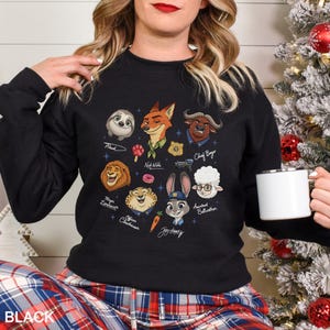 May include: Black sweatshirt featuring cartoon characters from Zootopia, including Flash, Nick Wilde, and Judy Hopps. The design includes character names and various themed icons. The word "BLACK" is printed at the bottom.
