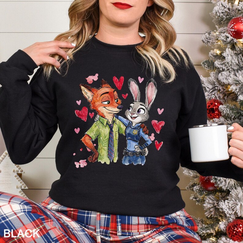 May include: Black sweatshirt featuring a watercolor illustration of Nick Wilde and Judy Hopps from Zootopia, surrounded by red hearts. Nick is wearing a green shirt and tie, while Judy is in a police uniform. The word "BLACK" is printed at the bottom.