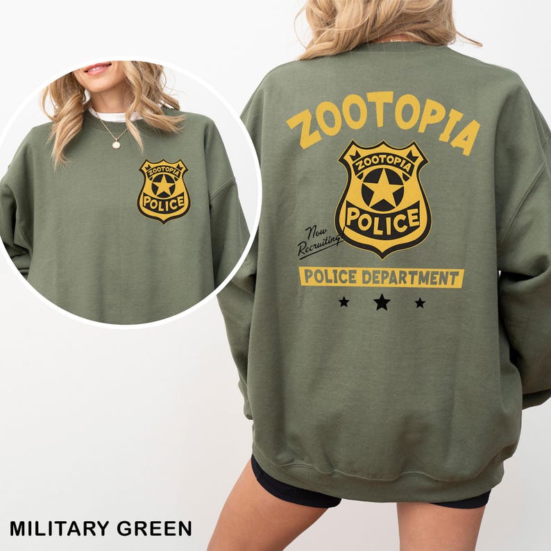 May include: Military green sweatshirt featuring a Zootopia Police Department badge on the front and back. The back design includes the word "Zootopia" in yellow, a police badge, and the text "Police Department". The sweatshirt is a casual style.