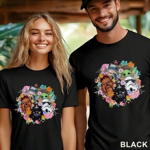 May include: Black t-shirts featuring a floral wreath design with Star Wars characters including Darth Vader, Chewbacca, and a Stormtrooper. The shirts are worn by a smiling man and woman.
