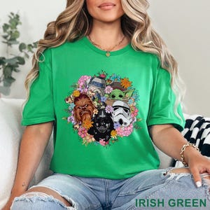 May include: Irish green t-shirt featuring a floral design with Star Wars characters including Chewbacca, Darth Vader, a Stormtrooper, R2-D2, and Grogu. The text "IRISH GREEN" is printed at the bottom of the image.