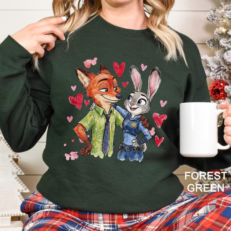 May include: Forest green sweatshirt featuring a watercolor illustration of Nick Wilde and Judy Hopps from Zootopia, surrounded by pink hearts. The text "FOREST GREEN" is printed at the bottom right.