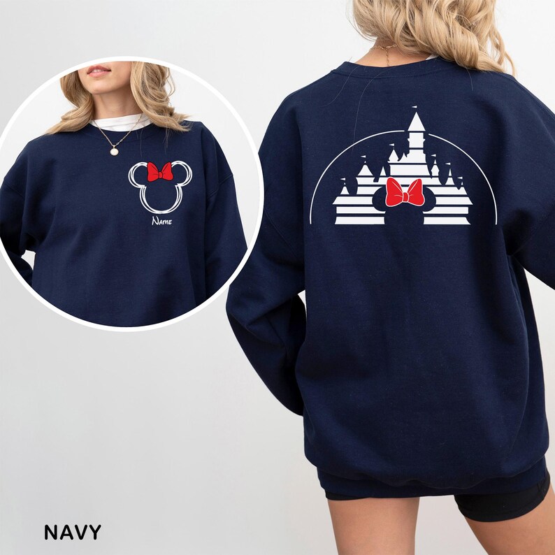 Pu&ograve; includere: Felpa blu navy con un design di Minnie Mouse bianco e un fiocco rosso, con la parola "Name". Il retro presenta un design a castello bianco e un fiocco rosso. La parola "NAVY" &egrave; in basso nell'immagine.