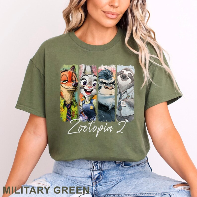 May include: Military green t-shirt with a vibrant graphic of Zootopia characters: Nick Wilde, Judy Hopps, Chief Bogo, and Flash. The text "Zootopia 2" is written in a cursive font below the characters. A casual, comfortable tee.
