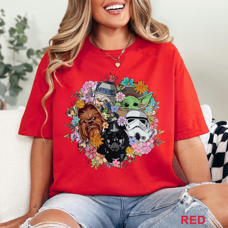 May include: Red t-shirt featuring a floral arrangement with Star Wars characters including Chewbacca, Darth Vader, a Stormtrooper, R2-D2, and Grogu. The word "RED" is printed at the bottom right.