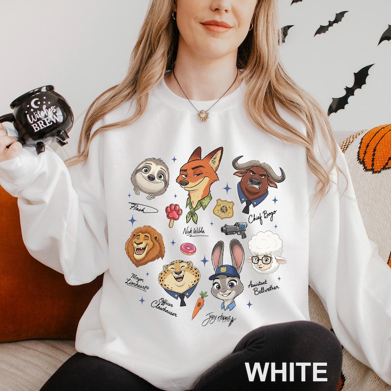 May include: White sweatshirt featuring cartoon illustrations of characters from Zootopia, including Flash, Nick Wilde, Chief Bogo, and Judy Hopps. The word "WHITE" is printed at the bottom. The sweatshirt is a crew neck style.