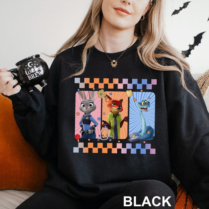 May include: Black sweatshirt with a design featuring three cartoon characters in rectangular frames with a chequered border. The characters include a rabbit, a fox, and a snake. The word "BLACK" is printed at the bottom.