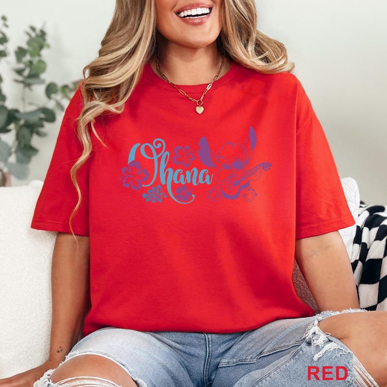May include: Red t-shirt with the word "Ohana" in blue script, accompanied by a purple and blue graphic of a character and flowers. The word "RED" is printed in the bottom right corner of the image.