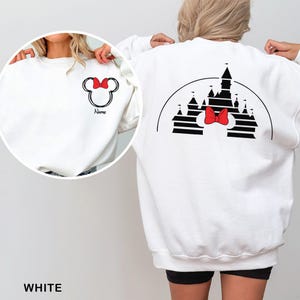 Pu&ograve; includere: Felpa bianca con un design di Minnie Mouse nero e fiocco rosso sul davanti e un design a castello sul retro. Il design frontale include la parola "Name". La felpa &egrave; a girocollo.