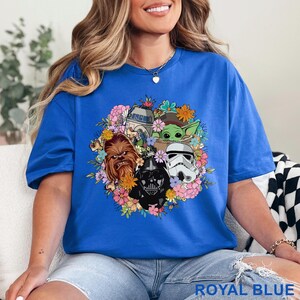 May include: Royal blue t-shirt featuring a floral arrangement with Star Wars characters including Darth Vader, Chewbacca, and a Stormtrooper. The shirt also features R2-D2 and Grogu. The text "ROYAL BLUE" is at the bottom.