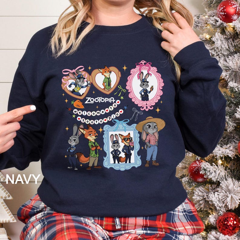 Op de afbeelding: Marineblauw sweatshirt met personages uit de film "Zootopia". Het ontwerp bevat ingelijste portretten van de personages, het woord "Zootopia" en decoratieve elementen. De sweatshirt heeft een ronde hals.