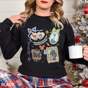 May include: Black Zootopia sweatshirt featuring various character portraits in ornate frames. The design includes images of Nick Wilde, Judy Hopps, and other characters. The word "Zootopia" is printed vertically on the left side of the sweatshirt.