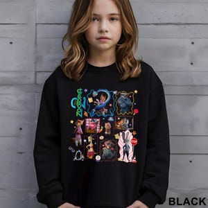 May include: Black sweatshirt featuring a colorful graphic of characters from the animated movie "Zootopia." The design includes the movie's title and various character illustrations. The word "BLACK" is printed in white at the bottom right.