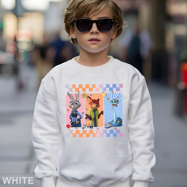 May include: White sweatshirt with a colourful graphic of three cartoon characters: a rabbit, a fox, and a snake. The sweatshirt has a crew neck and long sleeves. The word "WHITE" is printed at the bottom of the sweatshirt.