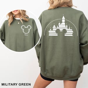 Pu&ograve; includere: Felpa verde militare con un contorno bianco della testa di Topolino sul davanti e un disegno di castello sul retro. La felpa ha un girocollo e maniche lunghe. La parola "Name" &egrave; stampata sotto la testa di Topolino sul davanti.