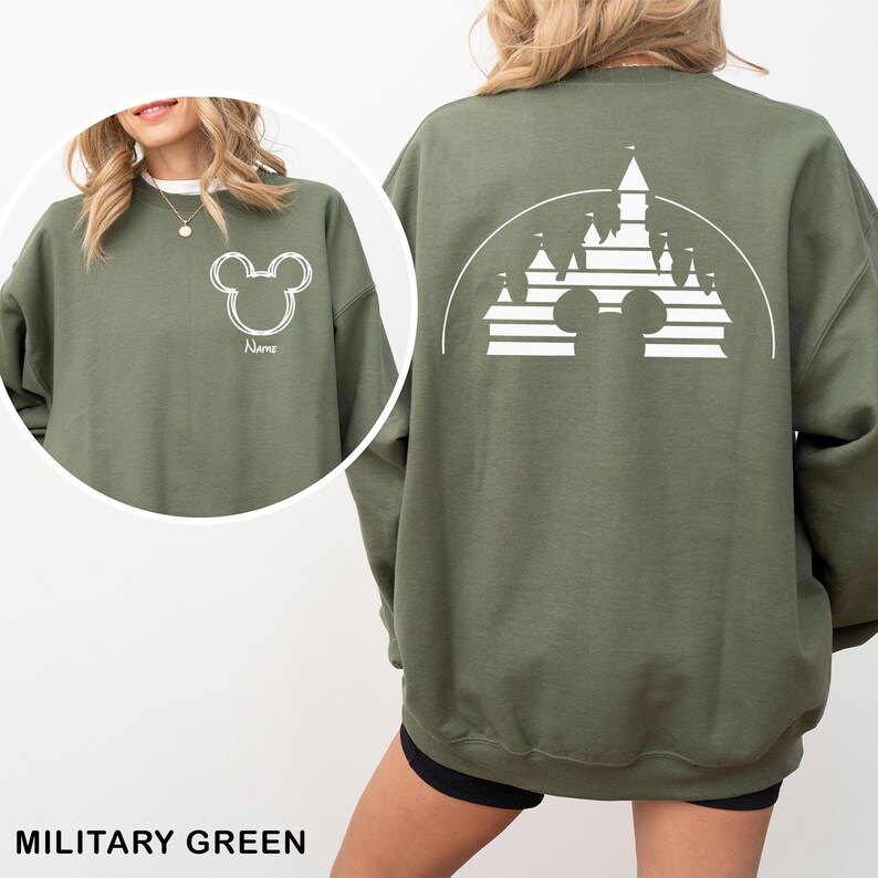 Pu&ograve; includere: Felpa verde militare con un contorno bianco della testa di Topolino sul davanti e un disegno di castello sul retro. La felpa ha un girocollo e maniche lunghe. La parola "Name" &egrave; stampata sotto la testa di Topolino sul davanti.