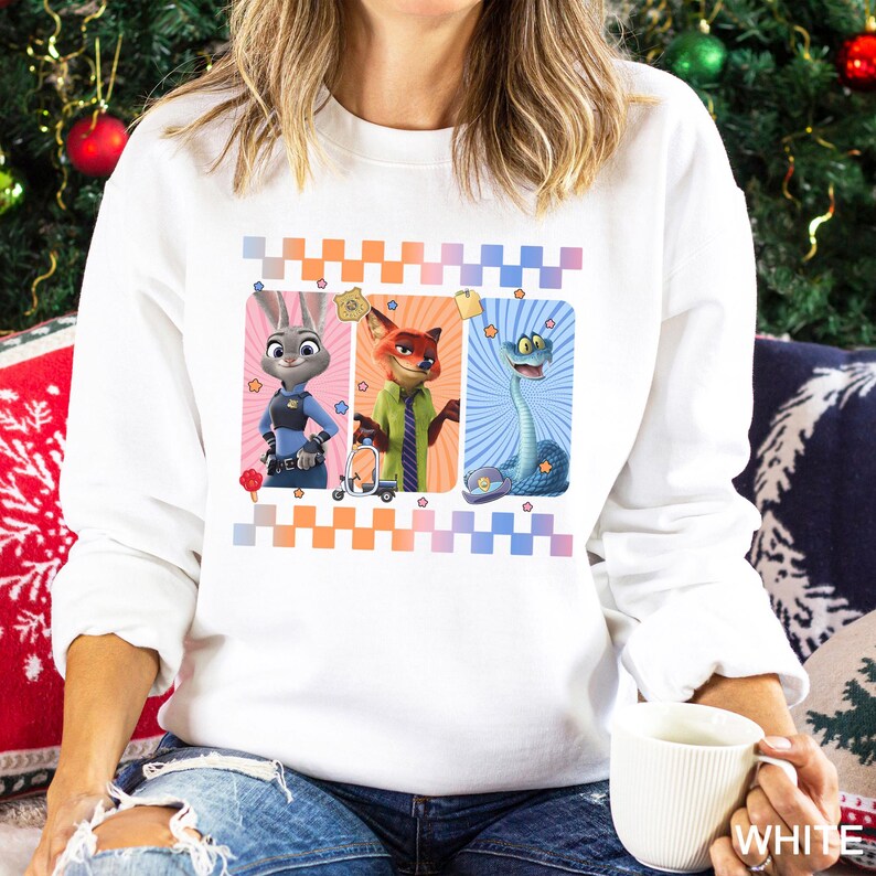 May include: White sweatshirt with a design featuring three cartoon characters in rectangular frames with a checkered border. The characters include a rabbit, a fox, and a snake. The sweatshirt is a crew neck style.