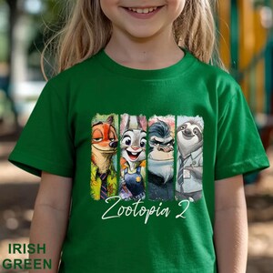 May include: A green t-shirt with a graphic of characters from the film Zootopia. The graphic shows Nick Wilde, Judy Hopps, a gorilla, and Flash the sloth. The text "Zootopia 2" is written in white script below the characters. The shirt is Irish green.