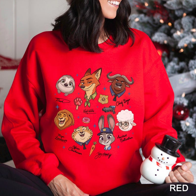 May include: A red sweatshirt featuring cartoon illustrations of characters from a movie. The design includes a sloth, fox, lion, and other animal characters. The word "RED" is printed in white at the bottom right.