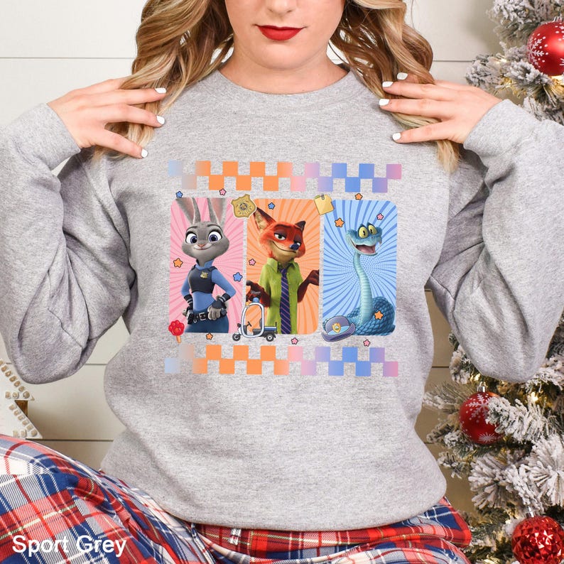 May include: A Sport Grey sweatshirt with a graphic of three cartoon characters: a bunny, a fox, and a snake. The design is set against a colorful checkered background. The sweatshirt has a crew neck and long sleeves.