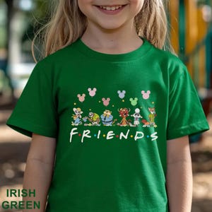 May include: Green t-shirt with a cartoon graphic and the word "FRIENDS" in white. The design includes Mickey Mouse head shapes in pink, blue, and green. The shirt is made of a soft material. The text "IRISH GREEN" is at the bottom.