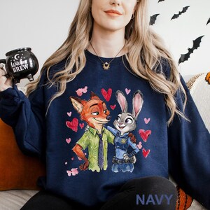 May include: Navy blue sweatshirt featuring a cartoon illustration of a fox and a rabbit embracing, surrounded by red hearts. The fox wears a green shirt and tie, while the rabbit is in a police uniform. The word "NAVY" is printed at the bottom.