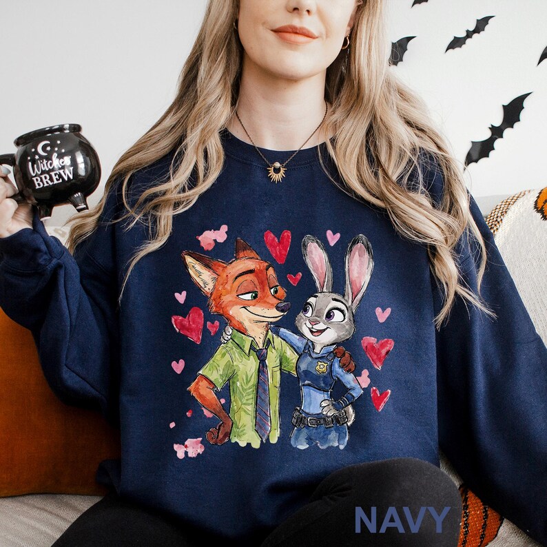 May include: Navy blue sweatshirt featuring a cartoon illustration of a fox and a rabbit embracing, surrounded by red hearts. The fox wears a green shirt and tie, while the rabbit is in a police uniform. The word "NAVY" is printed at the bottom.