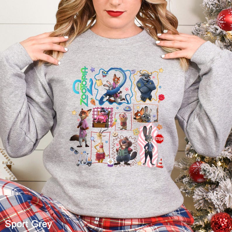 May include: Sport Grey sweatshirt featuring a colorful graphic of characters from the animated movie Zootopia. The design includes the movie title and various character illustrations. The sweatshirt is a long-sleeved, crew neck style.