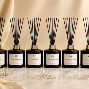 May include: Six matte black glass reed diffusers with gold collars and black reeds. Each bottle features a white label with the 6S logo and scent names: Still Bloom, Lumiere Rouge, Shoreline, Driftwood Creme, Crimson Cream, and Green Haven, 200ml.