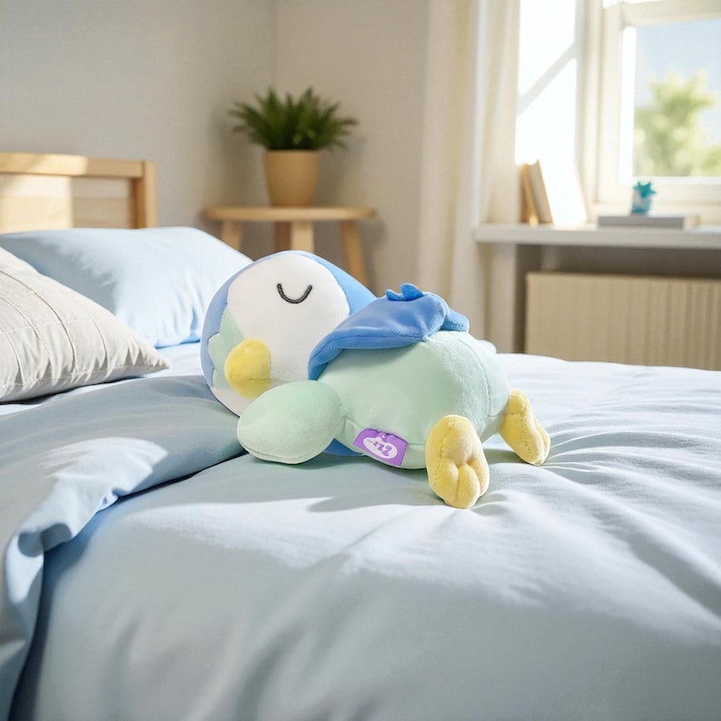 Puede incluir: Un peluche de p&aacute;jaro en tonos azules, verdes y amarillos descansa sobre una cama azul claro. El juguete tiene una cara sonriente y est&aacute; tumbado de lado. El fondo incluye una cama, almohadas, una ventana y una peque&ntilde;a mesa con una planta.