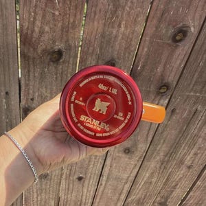 May include: A red Stanley brand tumbler base with a 40oz capacity, featuring a gold bear logo, the text 'DESIGNED IN SEATTLE WA', 'MANUFACTURED IN CHINA', 'BPA FREE', 'DISHWASHER SAFE', 'DO NOT MICROWAVE', and 'USING STRAW WITH HOT DRINKS MAY SCALD'.