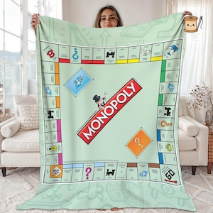 May include: A light green fleece blanket featuring a large Monopoly board game graphic. The design includes the iconic red Monopoly logo, the character Rich Uncle Pennybags, property spaces, Chance and Community Chest cards, and the Go corner.