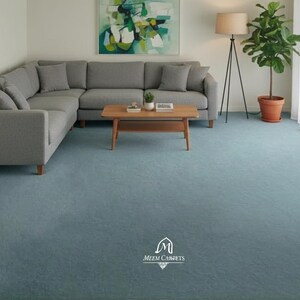 Könnte beinhalten: Ein modernes Wohnzimmer mit hellblauem Teppich, einem grauen Ecksofa und einem Couchtisch aus Holz. Eine Stehlampe und eine Topfpflanze ergänzen die Einrichtung. Das Bild zeigt auch ein Gemälde und weiße Vorhänge.
