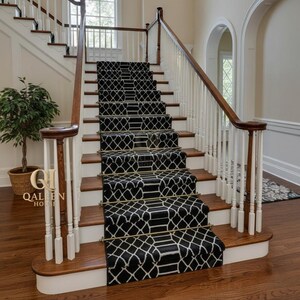 May include: A staircase with a black and white patterned runner. The runner features a geometric design and is installed on wooden steps with white risers. The staircase has a wooden handrail and white balusters.