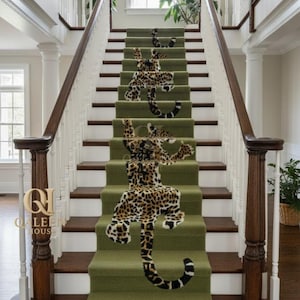 May include: A staircase with green carpet runners decorated with a leopard print design. The stairs have white risers, dark wood steps, and a white banister with a dark wood handrail. The QALEEN HOUSE logo is visible.