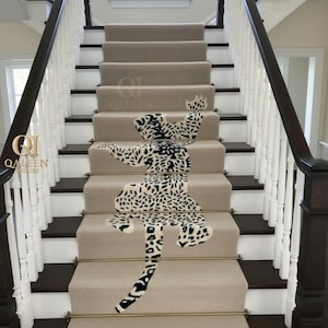 Puede incluir: Escalera alfombrada beige con un diseño de estampado de leopardo. El patrón de leopardo es blanco y negro y cubre el centro de las escaleras. Las escaleras tienen detalles de madera marrón oscuro y barandillas blancas. La marca "QALEEN HOUSE" es visible.