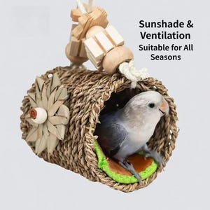 May include: A woven birdhouse with a small bird inside. The birdhouse is made of natural fibres and has a flower-shaped decoration on the side. The text "Sunshade & Ventilation Suitable for All Seasons" is visible.