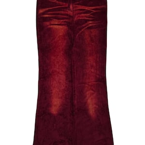 Peut inclure: Pantalon en velours côtelé bordeaux à jambe évasée. Le pantalon est suspendu à un cintre sur fond blanc. Le tissu a un aspect texturé avec des zones plus claires.
