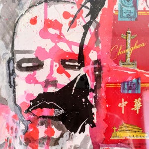 Peut inclure: Œuvre d'art abstraite en techniques mixtes représentant un visage avec des traits noirs et blancs, recouvert d'éclaboussures de peinture rose et rouge. Le fond comprend des rectangles rouges avec du texte et des illustrations chinois.