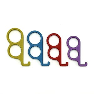 May include: A set of four handheld tools in yellow, blue, red, and purple. Each tool features two circular finger holes stacked vertically and a small hook extending from the bottom, designed with a smooth, matte finish and a flat profile.